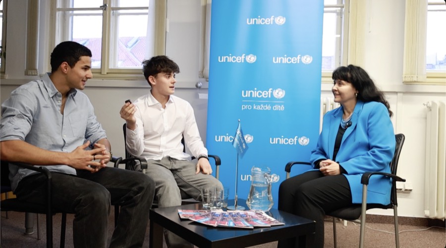 Dva z organizátorů při rozhovoru v kanceláři UNICEF, před modrým bannerem s logem
